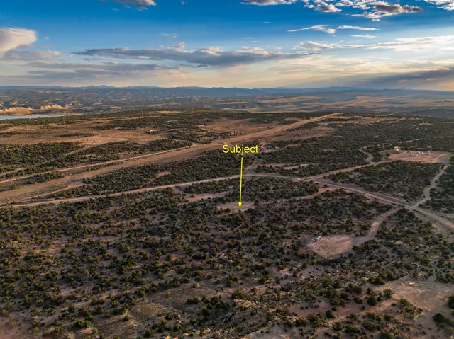 Expansive desert landscape featuring natural scrub brush and dirt roads