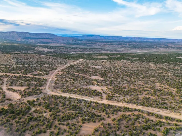 Expansive desert landscape featuring natural scrub vegetation and distant mountain ranges under a partly cloudy sky