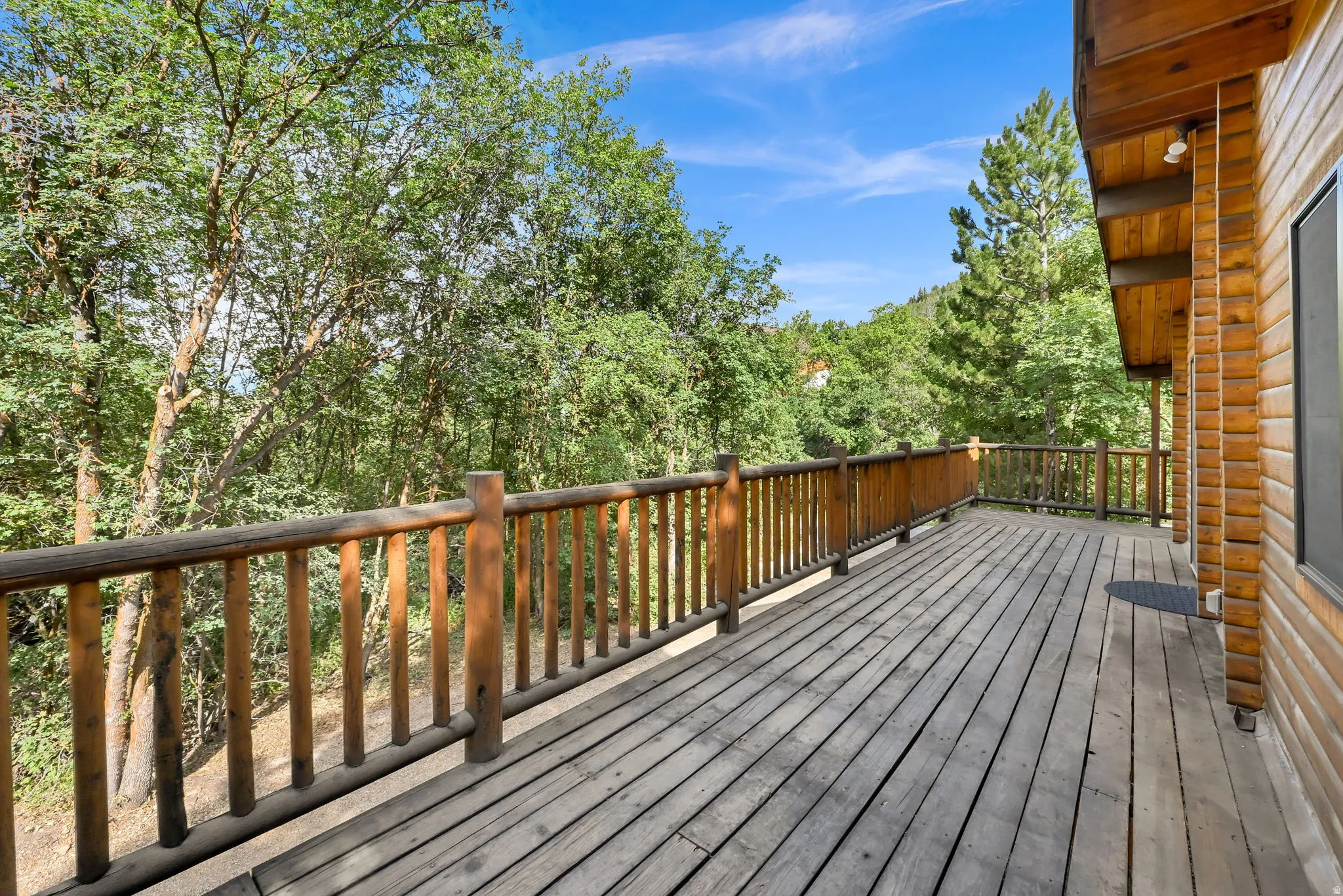 Expansive outdoor deck featuring wood plank flooring and log railing
