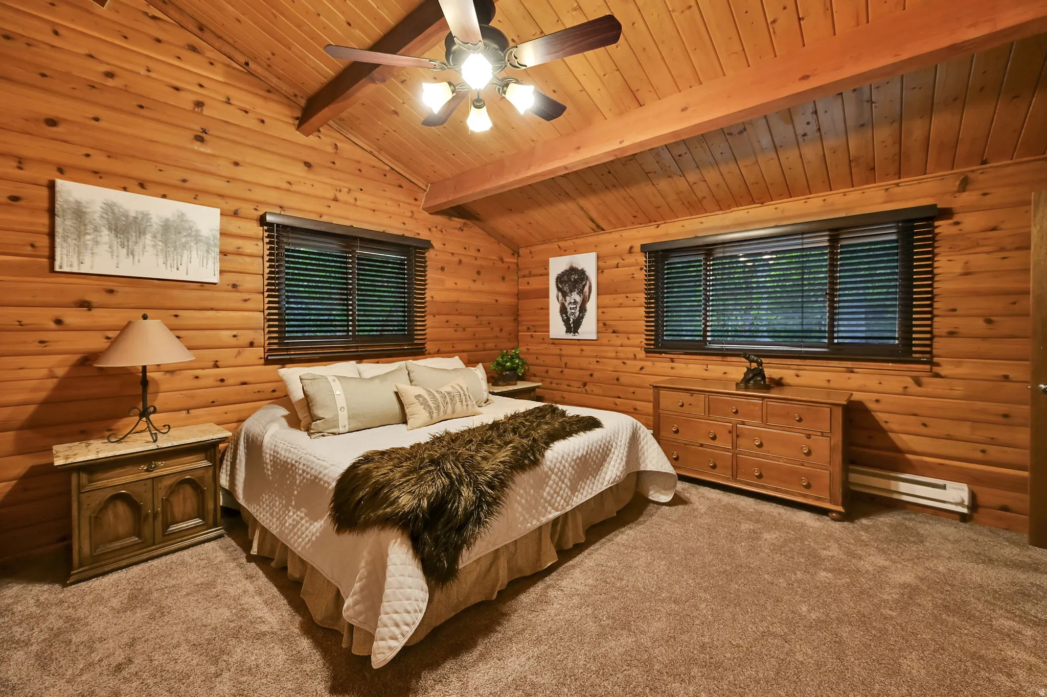 Wood-paneled room featuring a vaulted ceiling with exposed beams, ceiling fan, and two windows with dark wood blinds