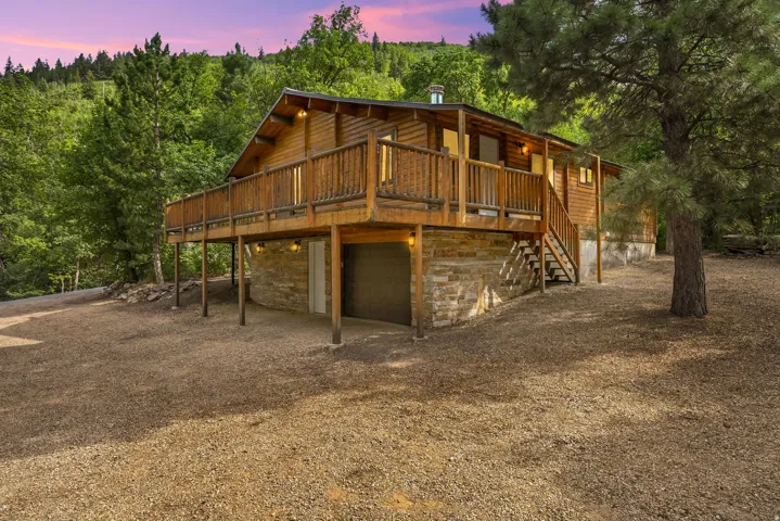 Wood-sided home featuring a stone foundation and an elevated wooden deck with railings
