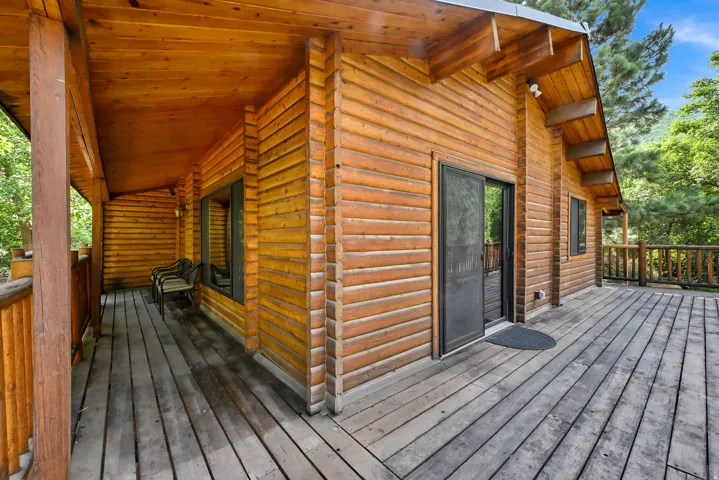 Wood-clad exterior featuring a spacious wood deck and an extended covered porch