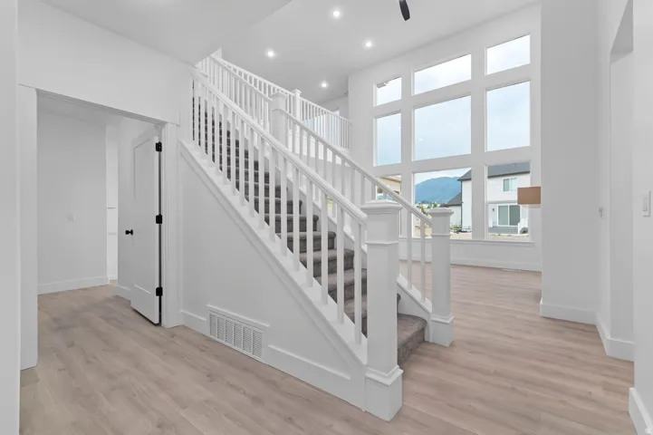 Bright entryway featuring a grand staircase with white banisters and gray carpeted treads