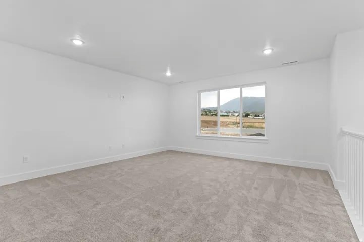 Spacious room with light neutral carpeting and white walls