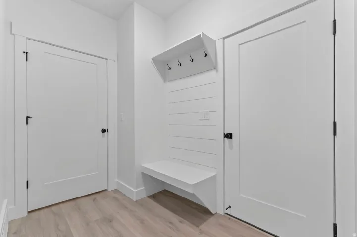 Entryway featuring a built-in bench, shiplap wall paneling, and wood-finish flooring