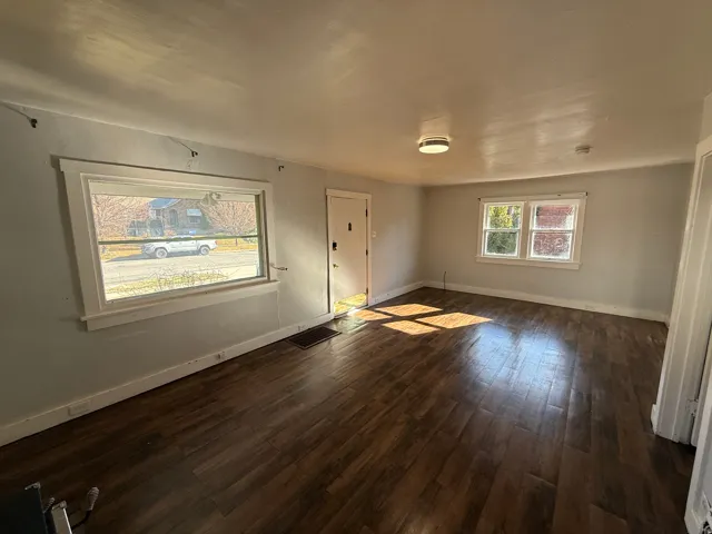 Spacious room featuring wood-finish flooring, light gray wall paint, and white trim