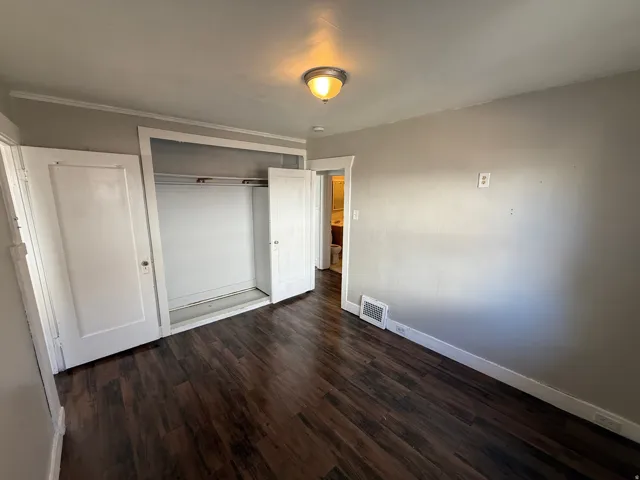 Bedroom featuring wood-finish flooring, a built-in closet with bi-fold doors, neutral wall paint, and a ceiling-mounted light fixture