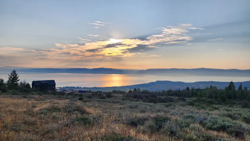 Expansive property featuring natural vegetation, distant water body, and a mountainous horizon