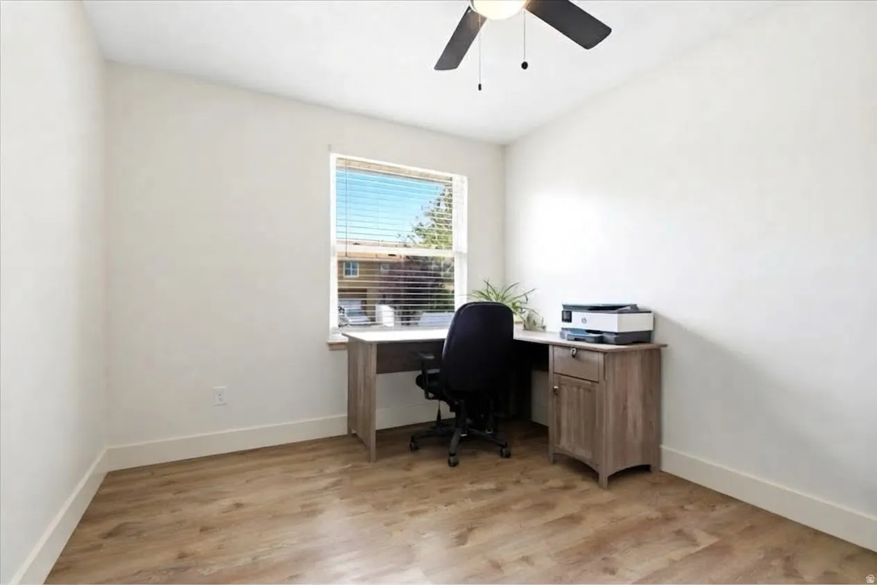 Wood-finish flooring, white walls, window with blinds, and a ceiling fan