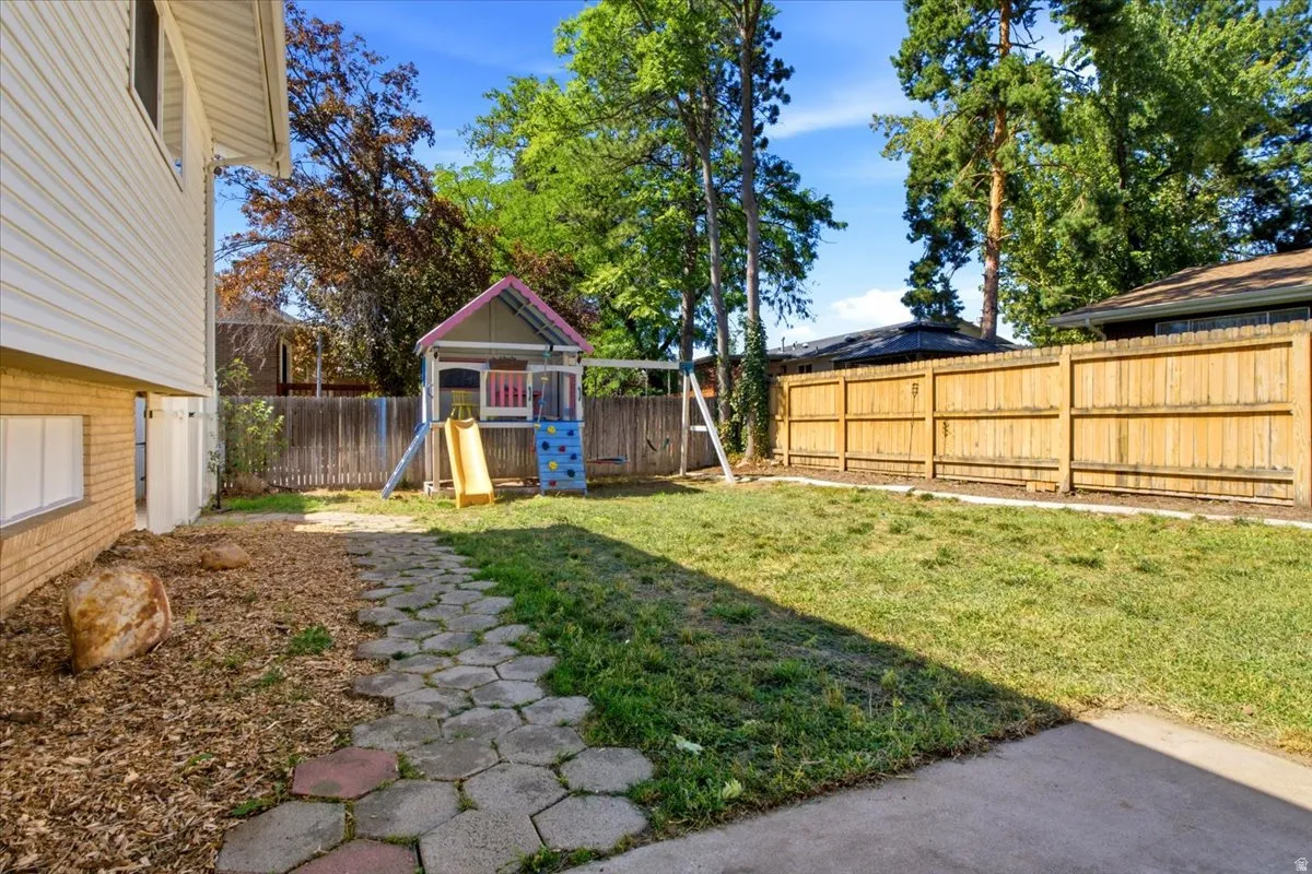 Expansive backyard featuring a wood privacy fence, concrete patio, and a paver stone pathway