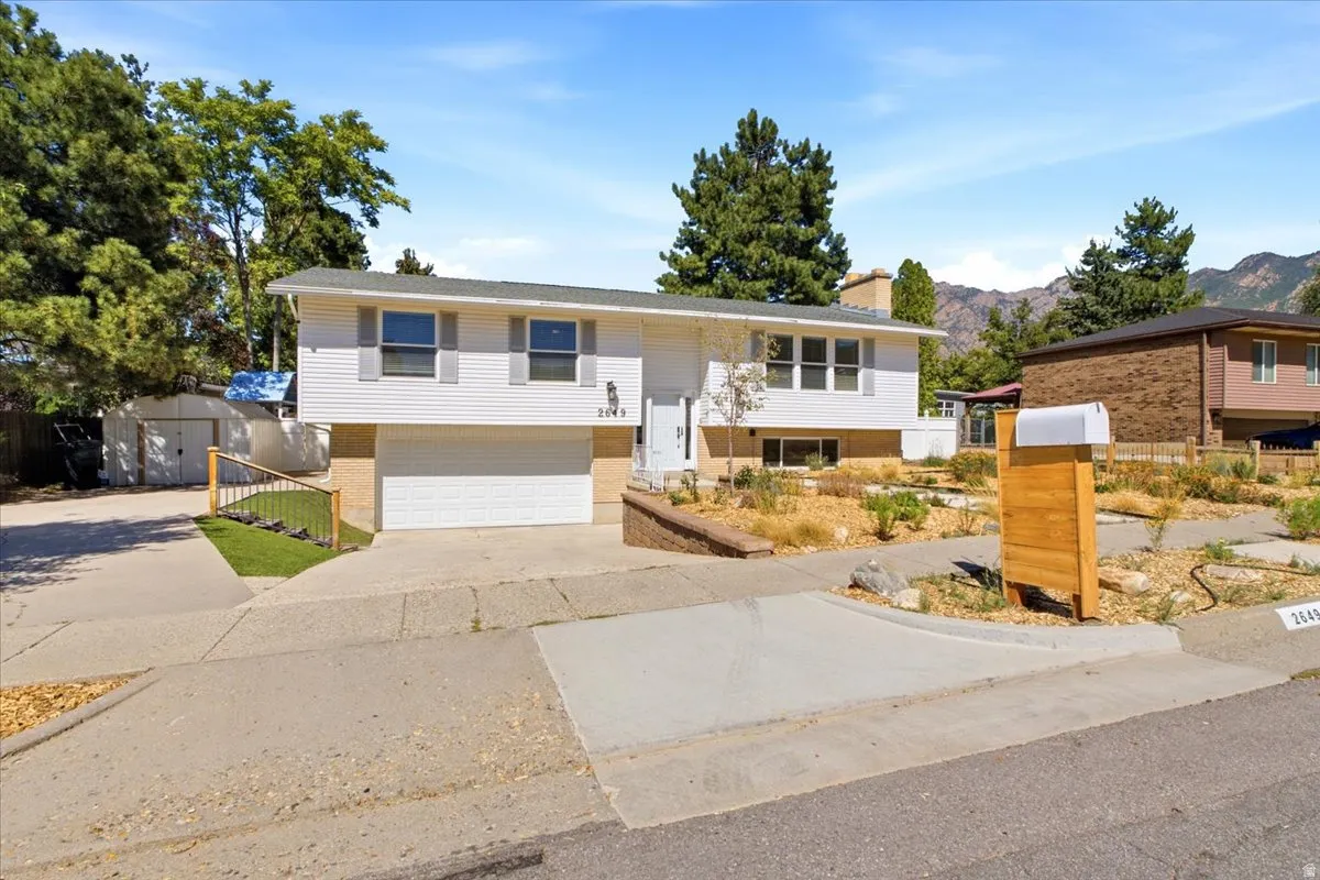 Split-level residence featuring white siding, an integrated garage, and a concrete driveway