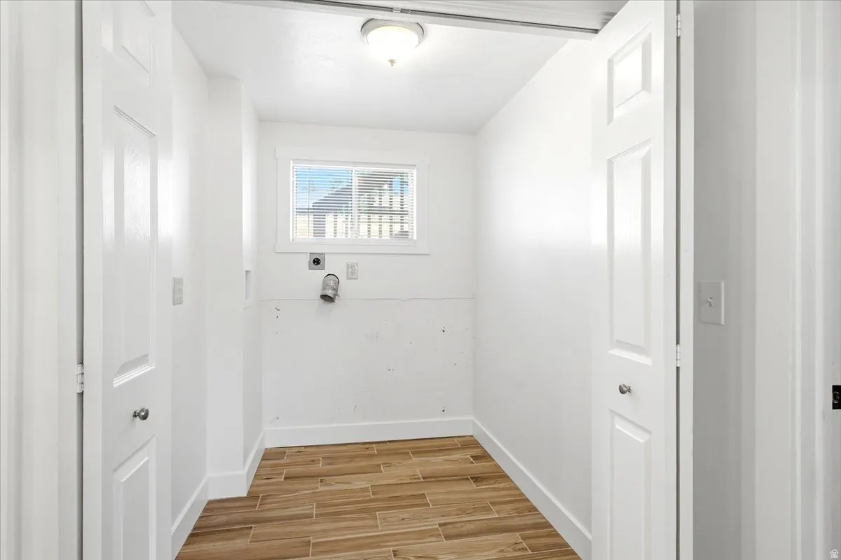 Laundry area with wood-finish flooring, a window, and paneled doors