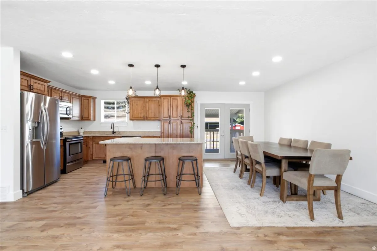 Open-concept living space with wood-finish flooring, recessed lighting, and a kitchen island with pendant lighting