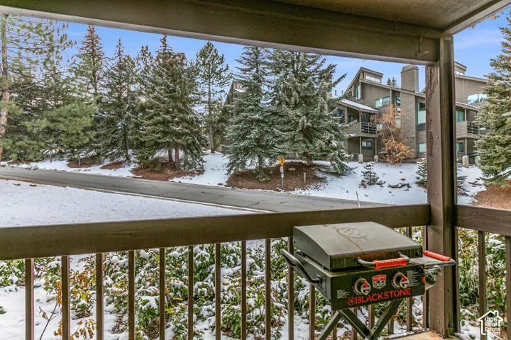 Private balcony featuring a wood railing and overlooking a snow-covered landscape