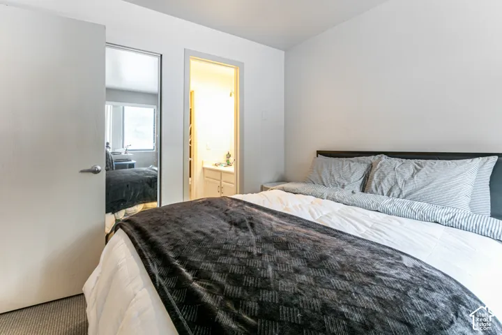 Bedroom featuring a dark headboard, light-colored walls, and a light gray carpeted floor