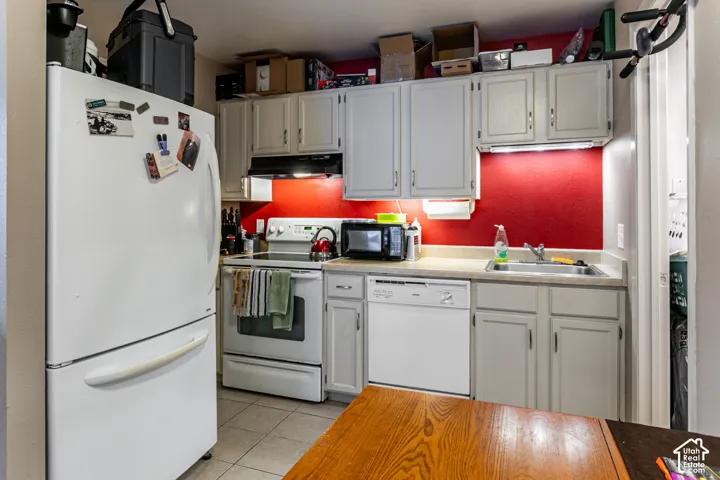 Kitchen featuring white appliances, light gray cabinetry, and a stainless steel sink with a single-handle faucet