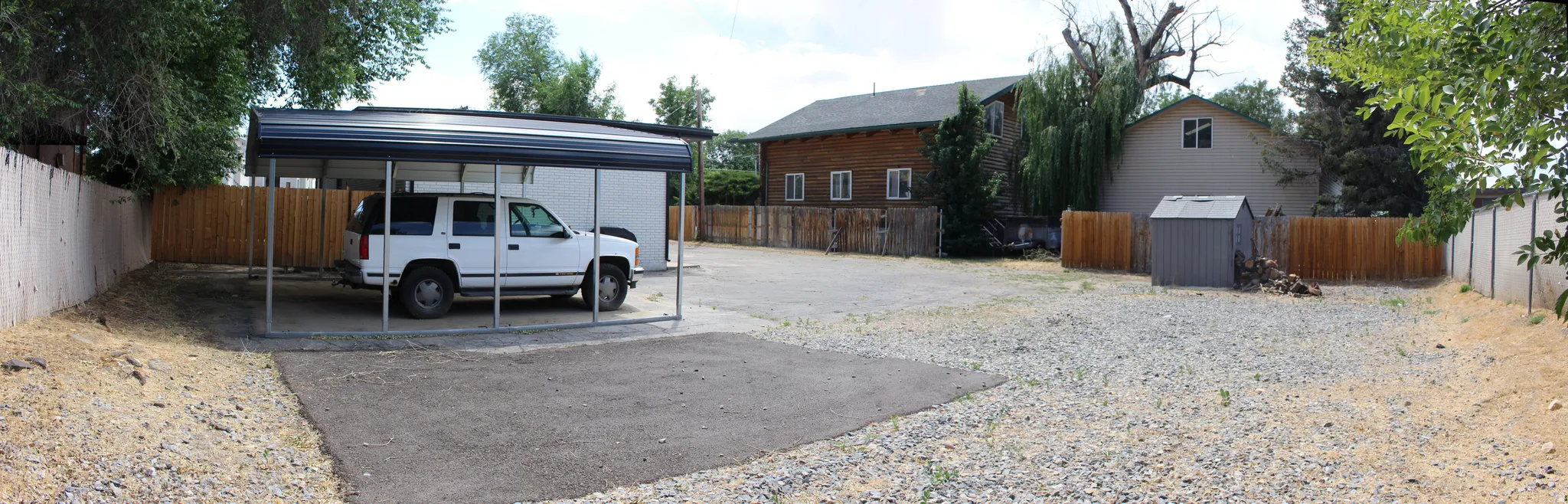 Spacious lot featuring a covered carport, wood privacy fencing, and a  storage shed