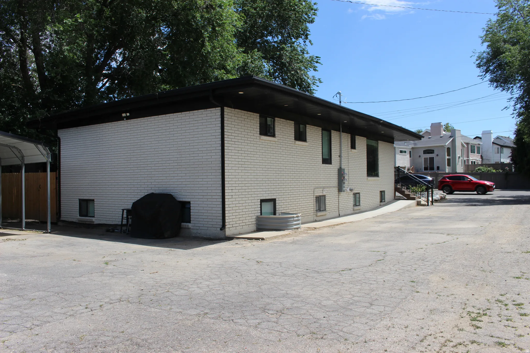White brick exterior with black trim, a flat roofline, and a paved parking area