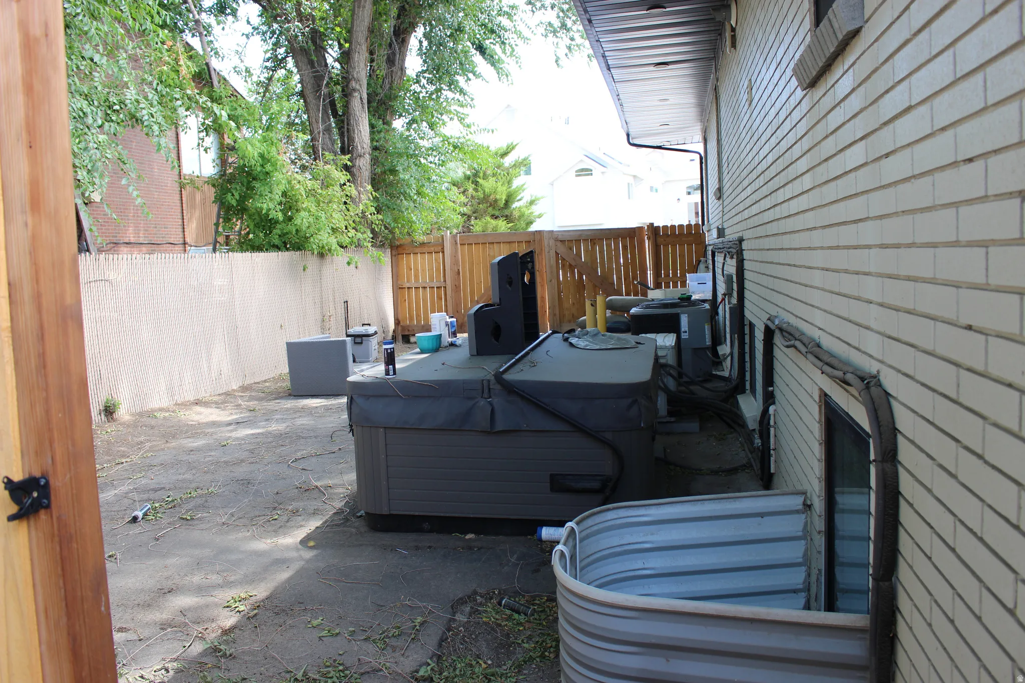 Rear exterior, a ground-level window well, and privacy fence