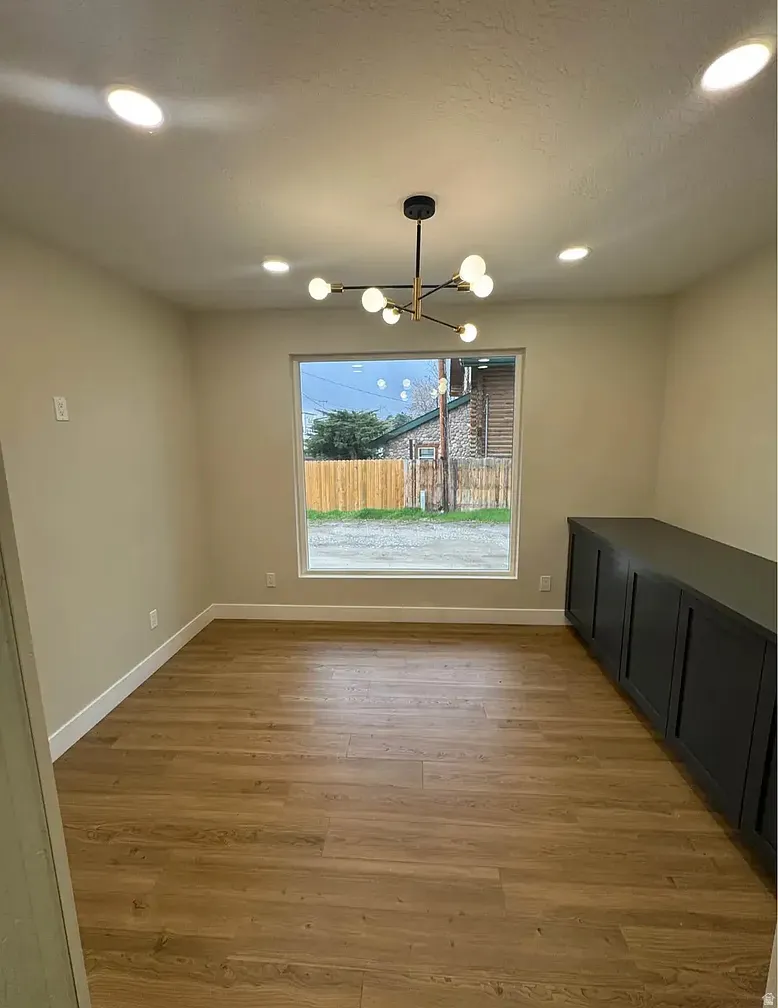 Open concept room featuring wood-finish flooring, a contemporary chandelier, recessed lighting, and a built-in dark cabinetry console