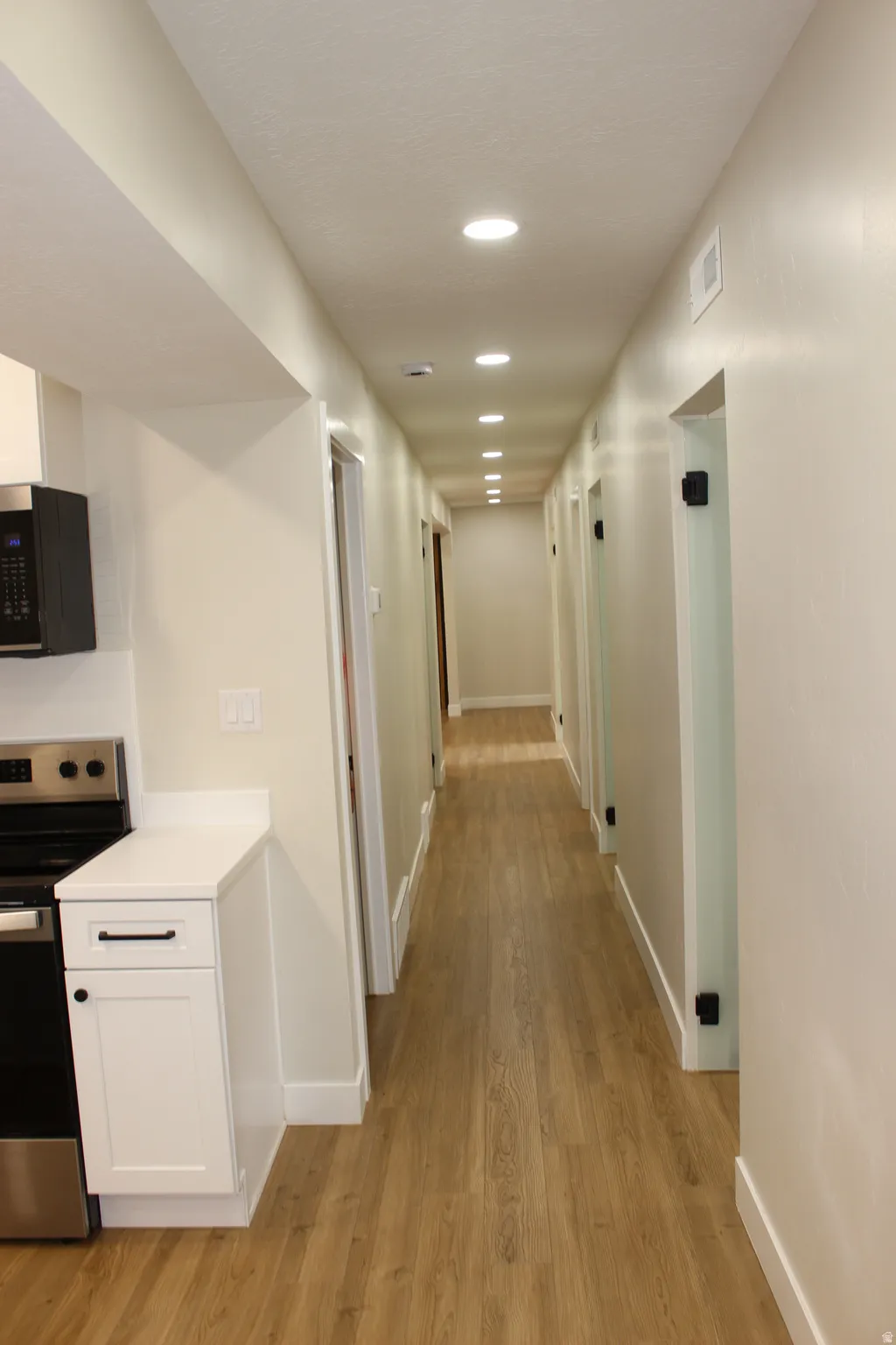 Long hallway featuring wood-finish flooring, recessed lighting, and crisp white trim