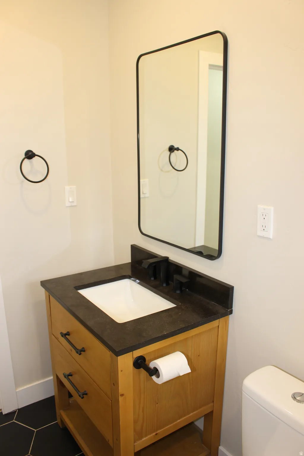 Bathroom vanity with an integrated sink, matte black faucet, and a rectangular framed mirror