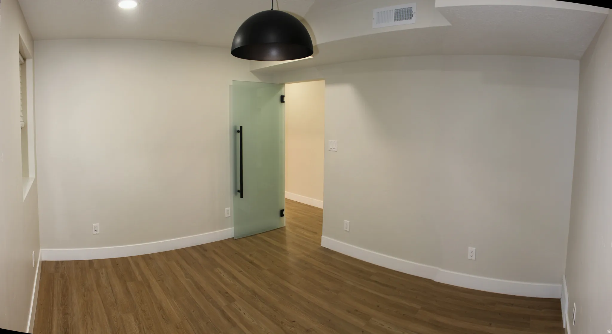 Open room with wood-finish flooring, light neutral walls, and white baseboards