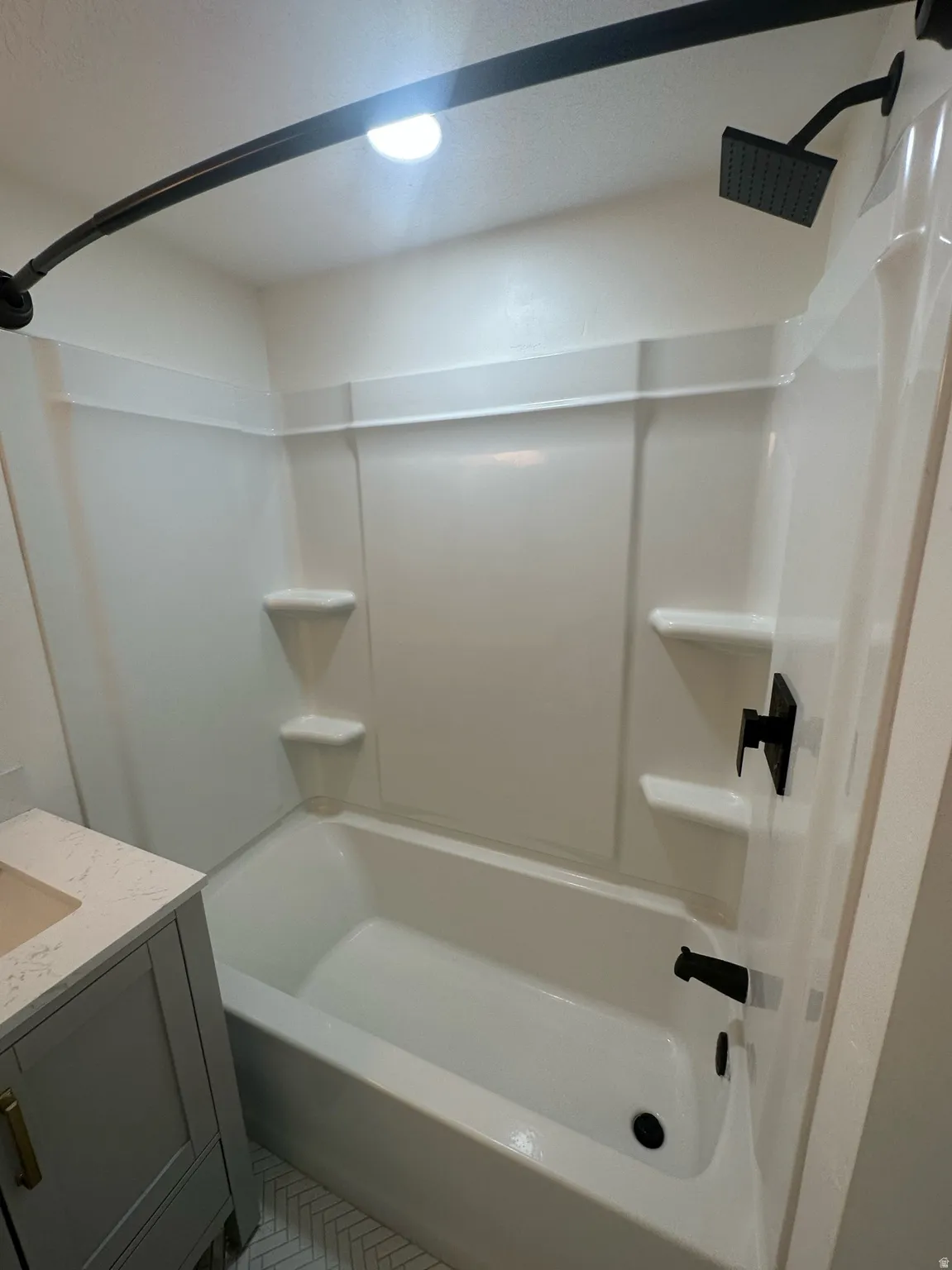 Bathtub and shower combination featuring a white surround, matte black fixtures