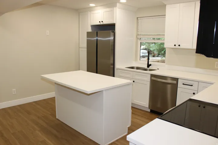 Modern kitchen featuring white shaker cabinetry and integrated stainless steel appliances