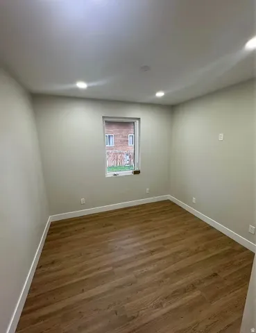 Recessed ceiling lighting, light-toned wall paint, wood-finish flooring, and white baseboards
