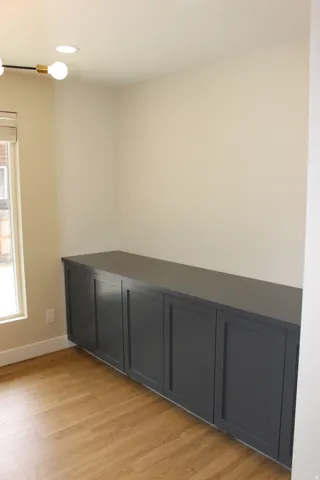 Built-in dark cabinetry with an expansive countertop, wood-finish flooring, a contemporary ceiling light fixture, and recessed lighting