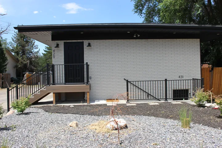 Modern exterior featuring white brick siding and a black front door