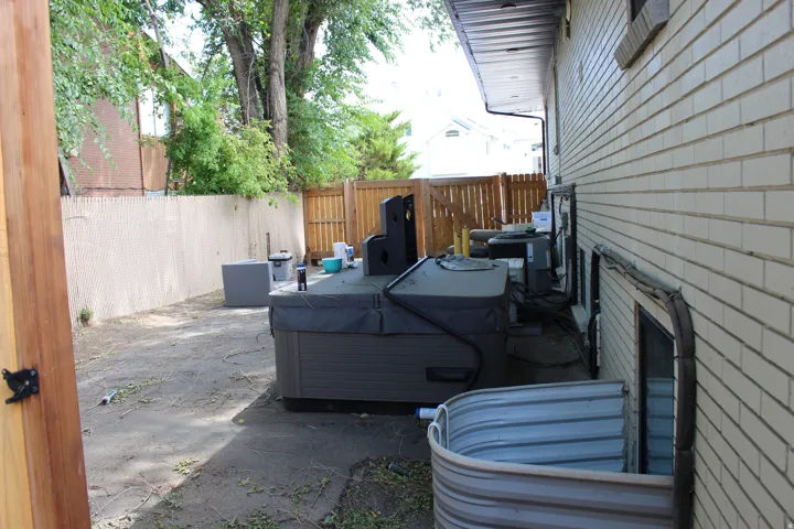 Rear exterior, a ground-level window well, and privacy fence