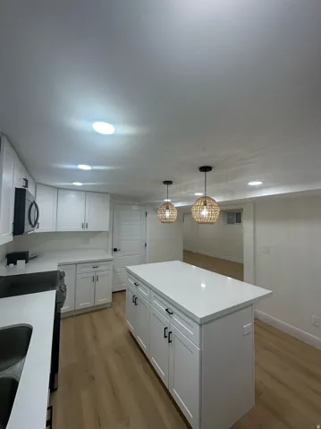 Large central island with white shaker cabinetry, light-colored countertops