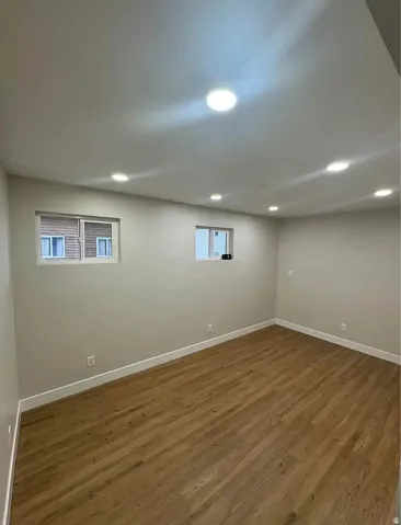 Spacious room featuring wood-finish flooring, recessed lighting, and two windows