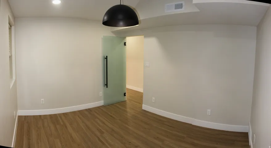 Open room with wood-finish flooring, light neutral walls, and white baseboards