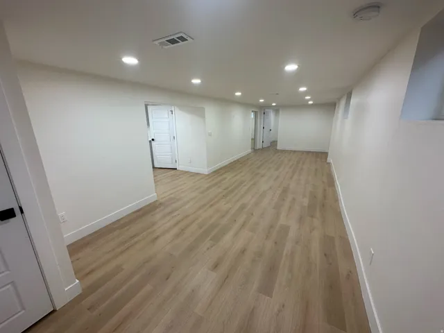 Open concept lower level featuring light wood-finish flooring and recessed lighting