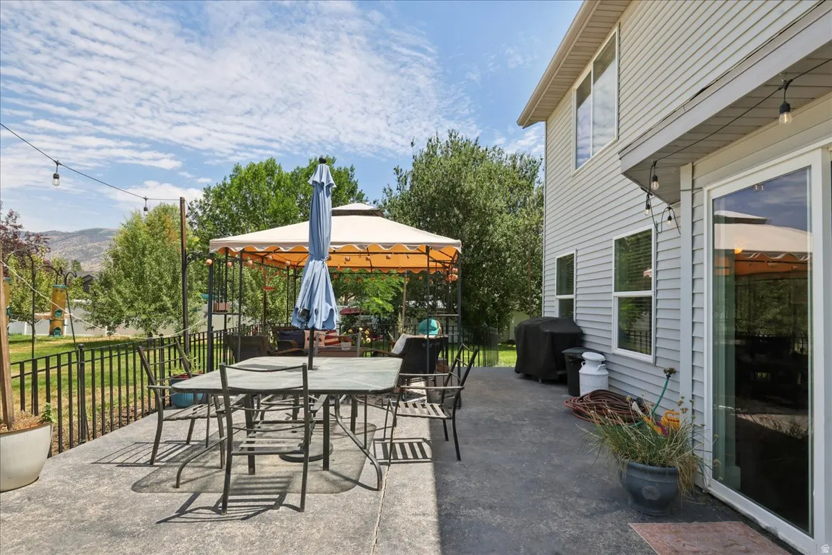 Spacious patio with stamped concrete flooring, siding exterior, black metal fencing, and string lights