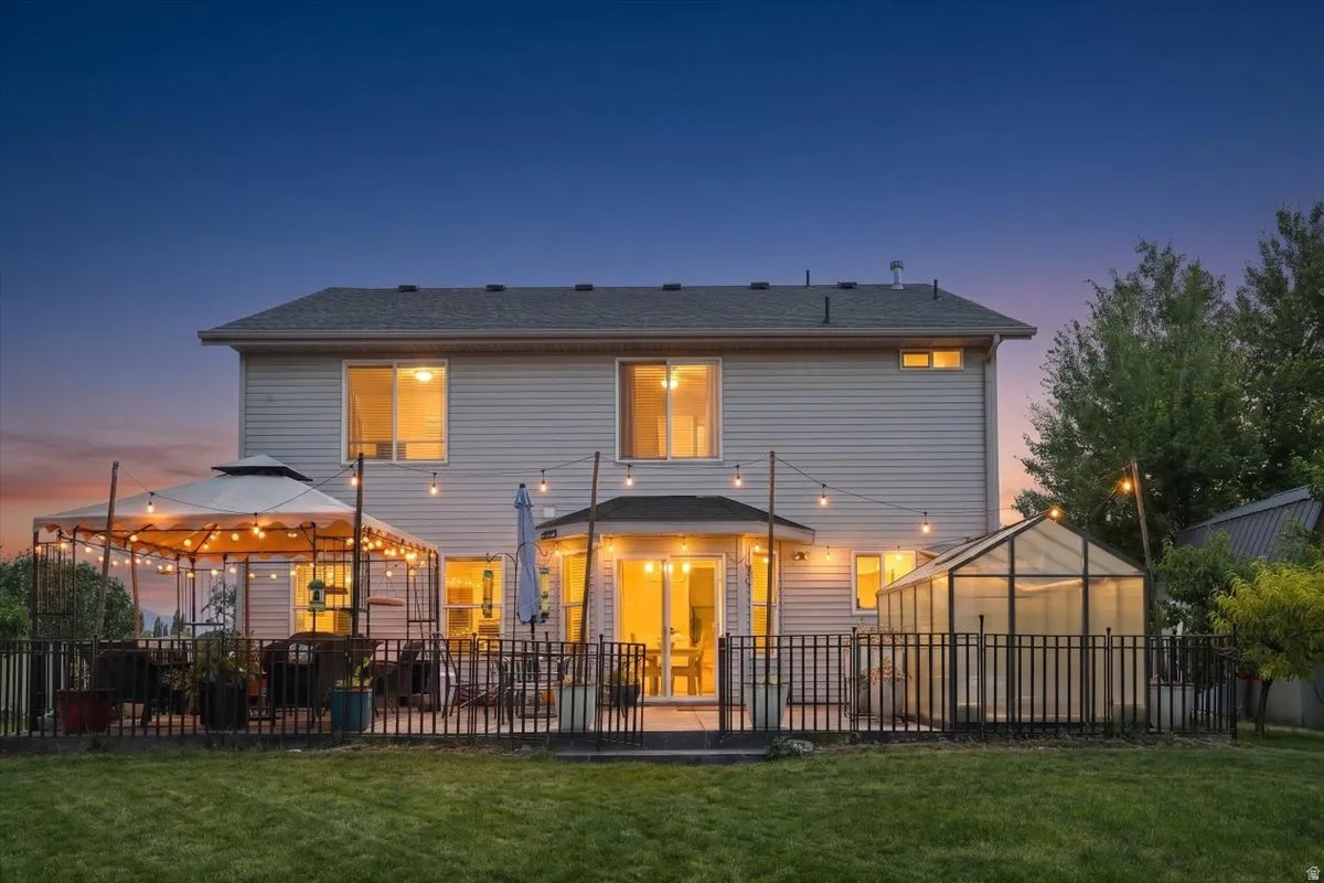 Rear exterior with a fenced yard, featuring a patio, a covered gazebo, and a glass-paneled greenhouse