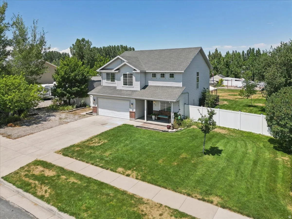 Two-story residence featuring a covered front porch, attached two-car garage, and a large front lawn