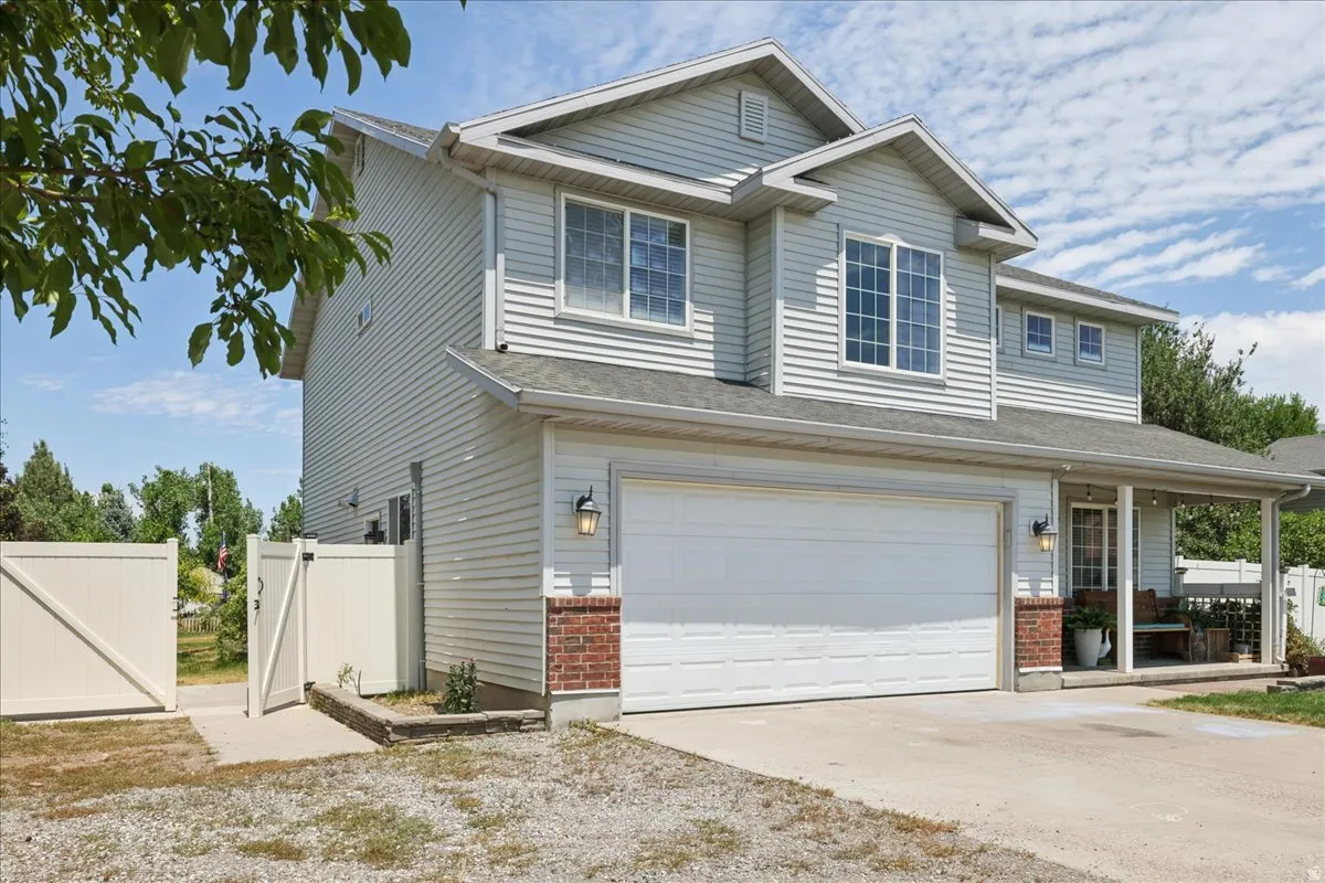 Two-story residence featuring light-colored siding, a two-car garage, and brick detailing