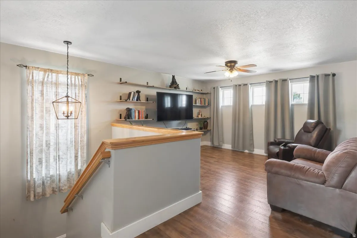 Living area featuring wood-finish flooring, a ceiling fan, and multiple windows