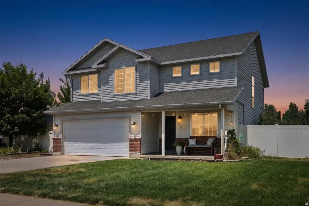 Two-story home featuring light grey siding, a covered front porch, and a two-car garage with a white door