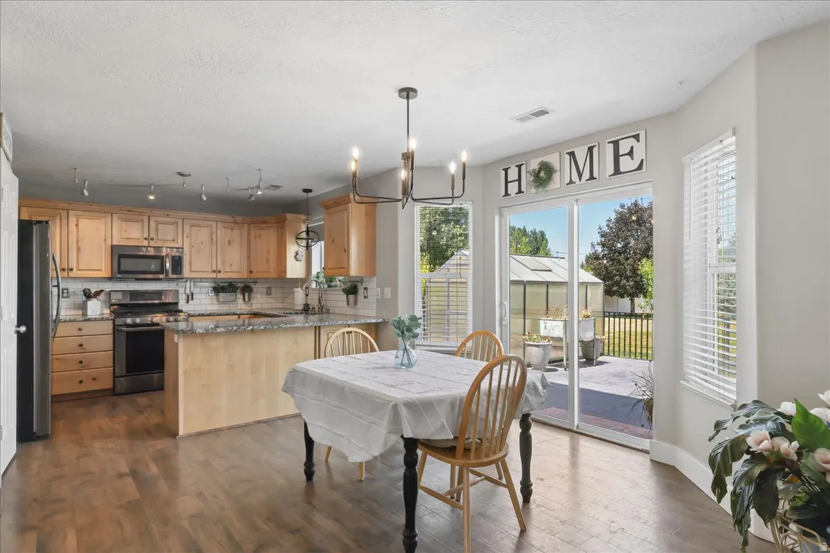 Open-concept kitchen and dining area featuring wood-finish flooring, light wood cabinetry, and stainless steel appliances