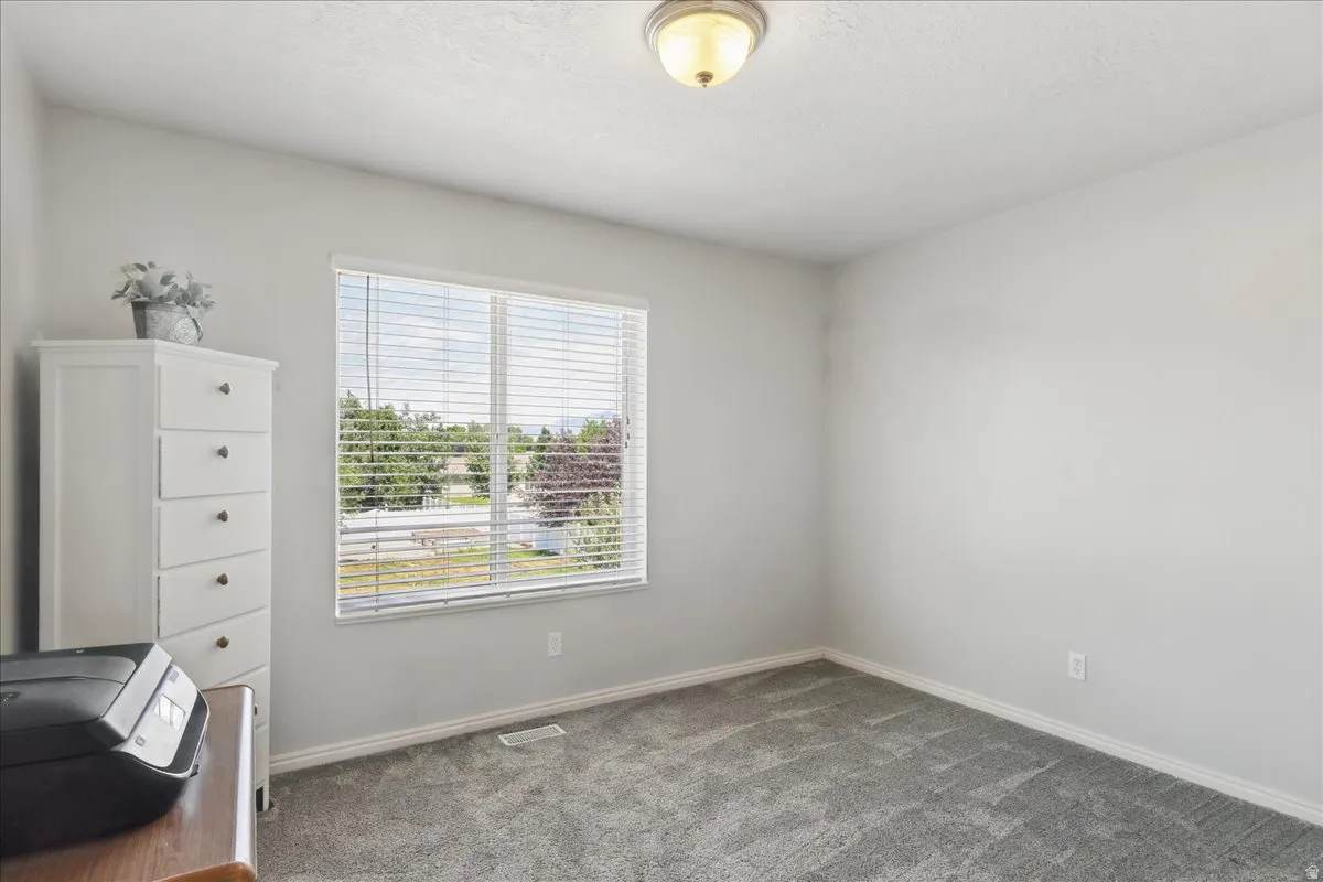 Spacious room featuring neutral grey walls and coordinating grey carpeting