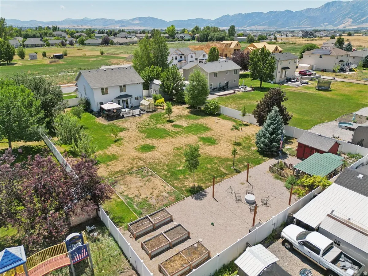 Expansive rear yard featuring a large gravel entertaining area, multiple raised garden beds, a storage shed, and mature trees
