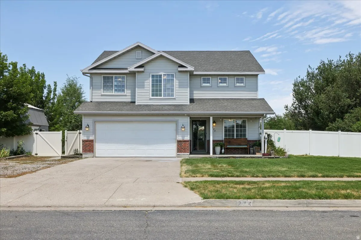 Two-story residence featuring light gray siding, a covered front porch, and an attached two-car garage
