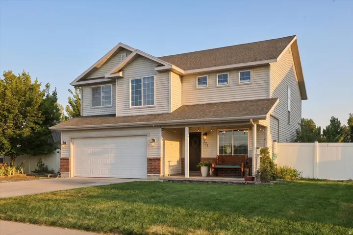 Two-story property featuring light-toned siding and a prominent front-facing garage with a white door