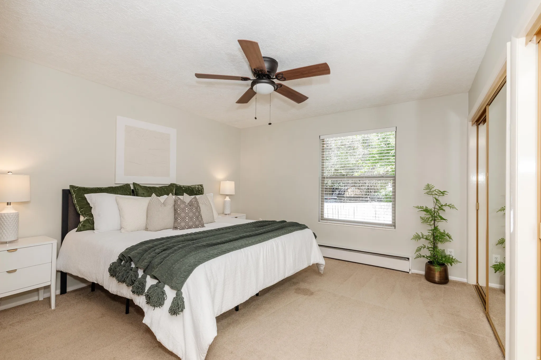 Carpeted bedroom featuring a window with blinds, a ceiling fan with integrated lighting, and a mirrored closet door