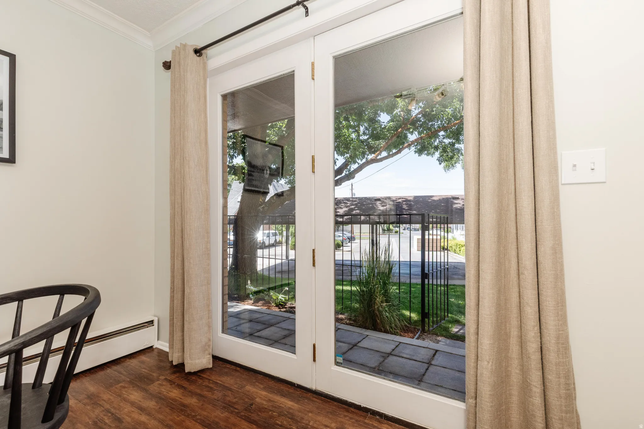 White French doors leading to an exterior patio with stone pavers and a black metal fence